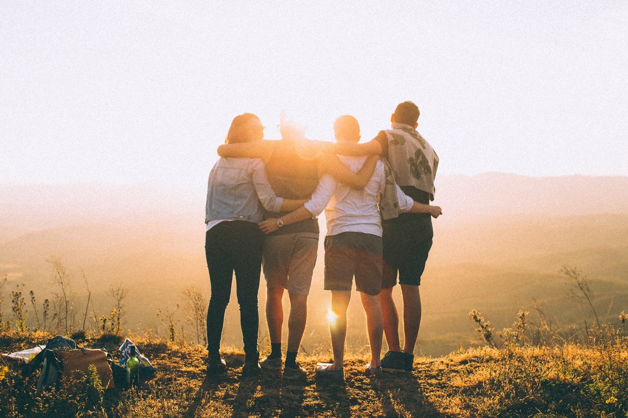 Freunde auf einem Berg die dem Sonnenuntergang zuschauen